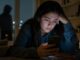 Ciberacoso en México: joven observa con preocupación mensajes recibidos en su teléfono celular.