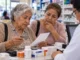 Adulta mayor y mujer de 60 a 64 años pagan medicamentos en una farmacia, reflejando cómo el gasto en salud presiona los apoyos del Bienestar.