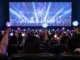 Seguidores del K-pop con lámparas luminosas durante una proyección musical en una sala de cine, imagen ilustrativa de HYBE Cine Fest 2026.