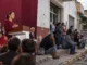 Imagen ilustrtativa generada con IA; Contraste entre discurso político de Morena y ciudadanos esperando atención en una calle mexicana, imagen del debate sobre el Humanismo Mexicano.