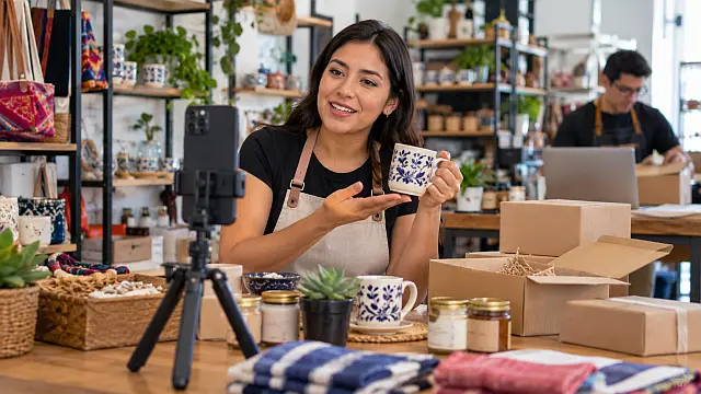 Emprendedora mexicana utiliza un teléfono móvil para grabar productos y promocionarlos por internet desde su pequeño negocio.
