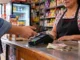 Cliente realiza un pago electrónico en una tienda de abarrotes mexicana donde también se utiliza efectivo.