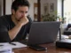 Persona preocupada frente a una computadora y un módem de internet, imagen sobre la Ley Antimemes, el riesgo de desconexión y la censura digital en México